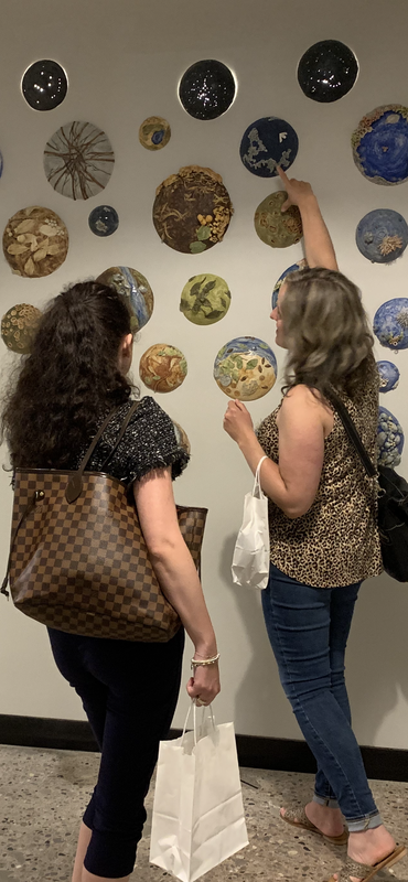 an image of two women standing in front of a ceramic wall installation